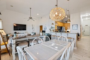 A modern kitchen with a central island, white dining table, and ceiling fans. - FFR307 - Still On Vacation by First Flight Rentals (Kill Devil Hills, NC 27948)