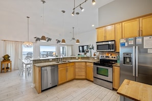 A modern kitchen with granite countertops, stainless steel appliances, wooden cabinets, and pendant lighting. - FFR307 - Still On Vacation by First Flight Rentals (Kill Devil Hills, NC 27948)
