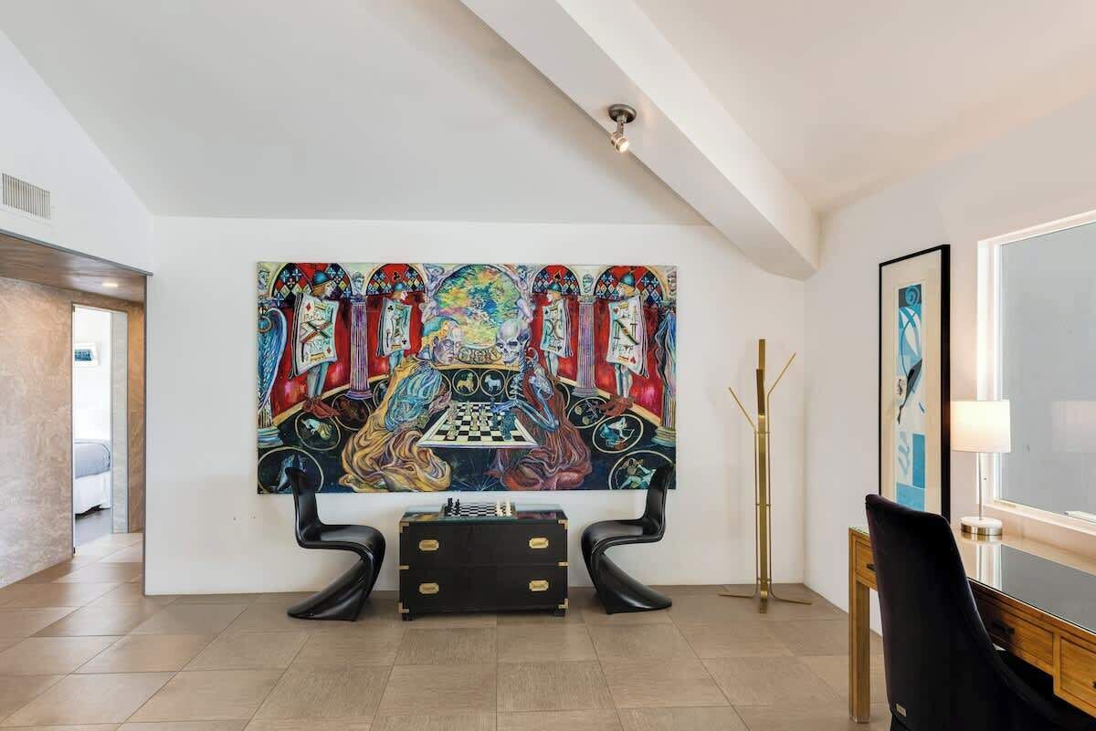 A room with a large abstract painting, a chessboard, and modern furniture.