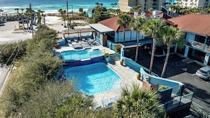 Ein Hotel mit Swimmingpool, Blick auf den Strand und mehreren Gebäuden.
