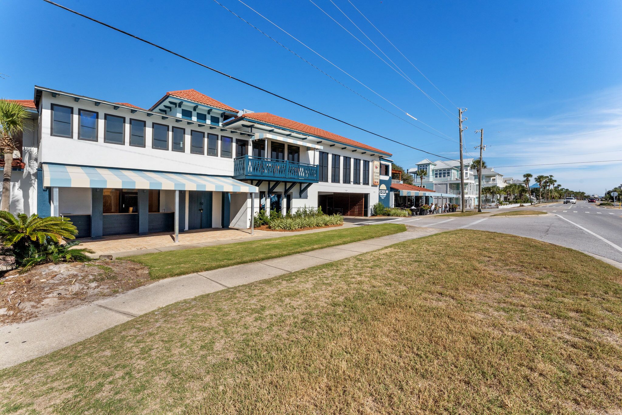 A two-story building with a balcony, a garage, and a well-maintained lawn.