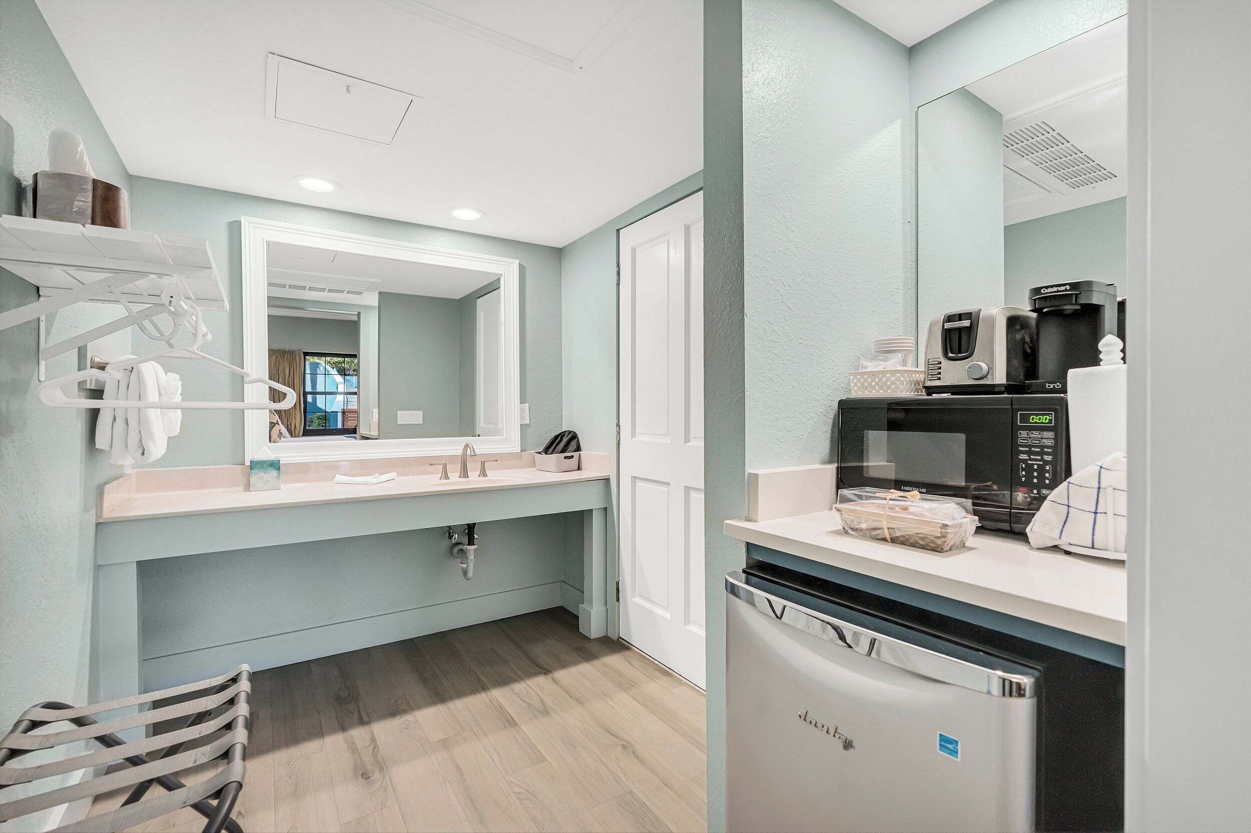 Une salle de bain équipée d’un lavabo, d’un miroir, d’un porte-serviettes et d’une machine à café.