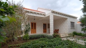 A modern house with a covered porch, a tiled exterior, and a garden area with various plants.