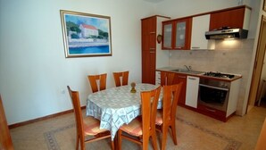 A compact kitchen with wooden cabinets, a gas stove, and a dining table with chairs.