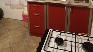 A compact kitchen with a gas stove, a sink, and a red cabinet. - Apartment in Stanići with Seaview, Balcony, Air condition, WIFI (634-3) (Stanici)