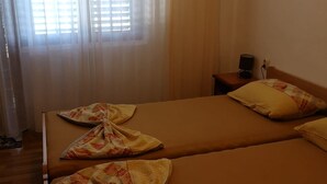 A room with two beds, a bedside table with a lamp, and a window with sheer curtains. - Apartment in Stanići with Seaview, Balcony, Air condition, WIFI (634-3) (Stanici)