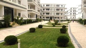 Un immeuble résidentiel moderne doté de nombreux balcons et d’une pelouse bien entretenue.