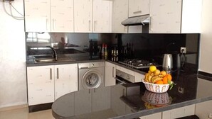 Une cuisine moderne avec des meubles blancs, un lave-linge encastré, une cuisinière et un évier.