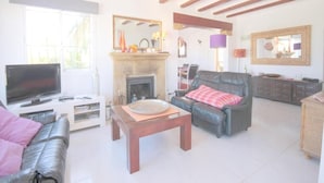 A living room with a fireplace, a television, a sofa, and a dining table. - Anna - Javea, Costa Blanca (Javea)