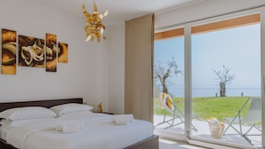 Een moderne slaapkamer met een groot bed, uitzicht op zee en kunst aan de muur.
