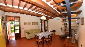 Un comedor con mesa de madera, sillas y techo con vigas a la vista.