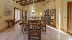 A dining area with a wooden table and chairs, a bookshelf, and a decorative wall piece.