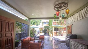 Un espace patio aménagé avec des meubles en bois, un barbecue et des lanternes suspendues.