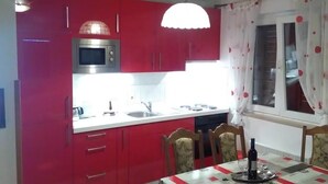 A kitchen with red cabinets, a microwave, and a dining table with chairs. - Apartment in Kožino with Seaview, Balcony, Air condition, WIFI (4262-1) (Kožino)