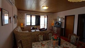 A cozy room with a sofa, dining table, and chairs. There is a television on a stand and a window with curtains. - Apartment in Kožino with Seaview, Balcony, Air condition, WIFI (4262-1) (Kožino)
