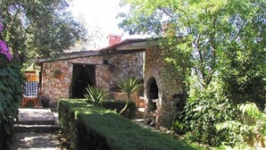 A stone building with an arched doorway, surrounded by lush greenery and a pathway leading to a seating area. - Studio apartment in Ražanj with Terrace, Air condition, WIFI (4597-1) (Ražanj)
