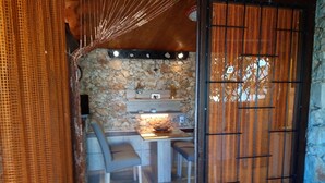 A cozy room with a stone wall, a small table with chairs, and a decorative item on the wall. - Studio apartment in Ražanj with Terrace, Air condition, WIFI (4597-1) (Ražanj)