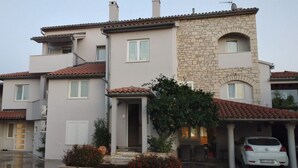 A multi-story residential building with a mix of stone and plaster exteriors, a tiled roof, and a covered carport. - Apartment in Medulin with Seaview, Balcony, Air condition, WIFI (112-5) (Medulin)