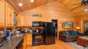 Ein Holzblockhaus-Innenraum mit Küche, Essbereich und Wohnzimmer.