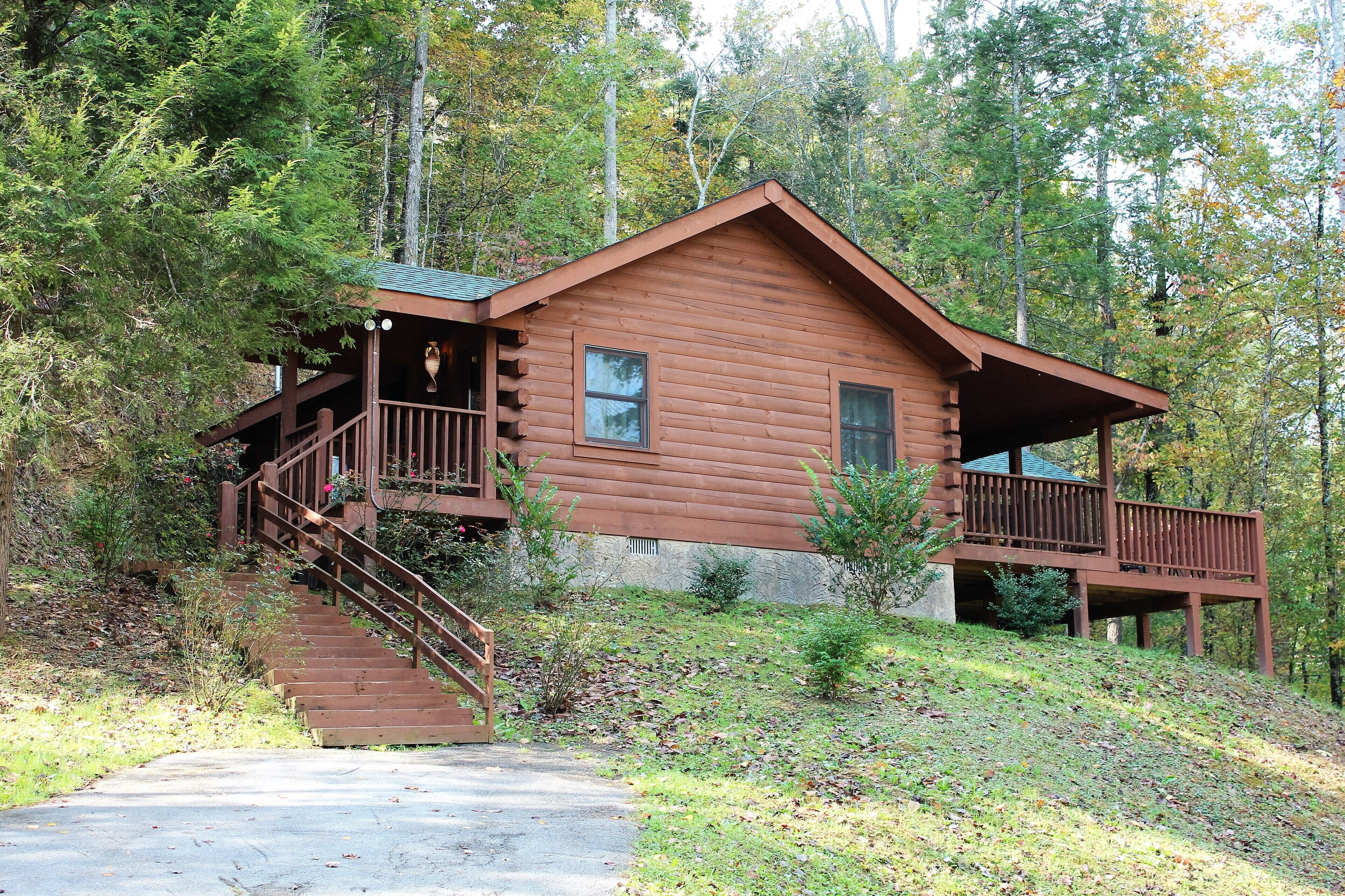 A wooden cabin with a porch and a staircase leading to a deck.