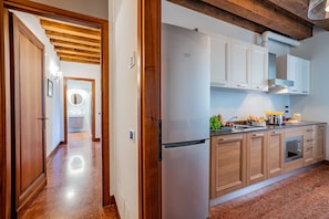 A kitchen with wooden cabinets, a stainless steel refrigerator, and a countertop with food items.