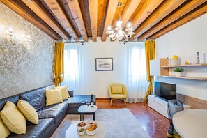 Un salón con sofá, sillón, mesa de centro y televisor.
