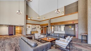 A spacious lobby with a large seating area, a wooden coffee table, and a stone accent wall. - Ski in/Ski Out! In Room Jacuzzi! (Breckenridge)