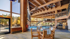 A spacious indoor area with a pool, wooden furniture, and a view of trees. - Ski in/Ski Out! In Room Jacuzzi! (Breckenridge)
