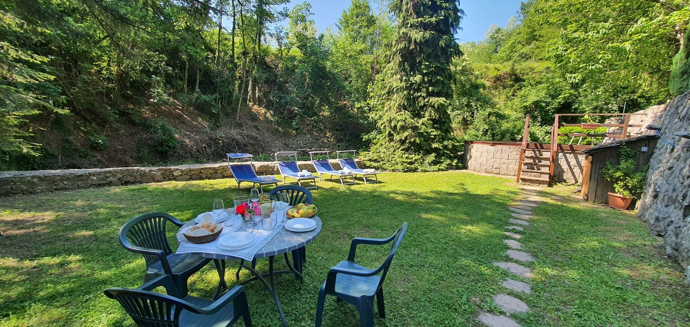 A patio with a table set for dining, surrounded by chairs and a sun lounger area.
