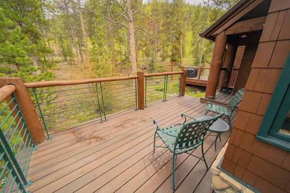 Une terrasse en bois avec une rambarde, une table et des chaises.