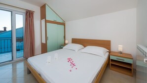Ein Hotelzimmer mit Bett, Nachttisch, Fenster mit Vorhängen und Blick auf einen Pool.