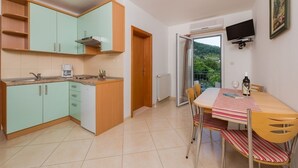 Eine kleine Küche mit türkisfarbenen Schränken, einer Holz Arbeitsplatte und einem Essbereich mit Tisch und Stühlen.