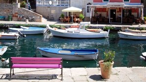 A waterfront scene with colorful buildings, a bench, and several boats docked at the marina. - Apartment in Veli Lošinj with Terrace, Air condition, WIFI, Washing machine (63-2) (Veli Lošinj)