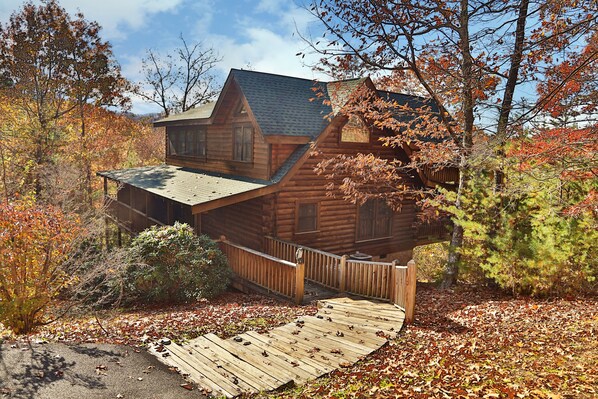 A log cabin with a steeply pitched roof, surrounded by autumn foliage.