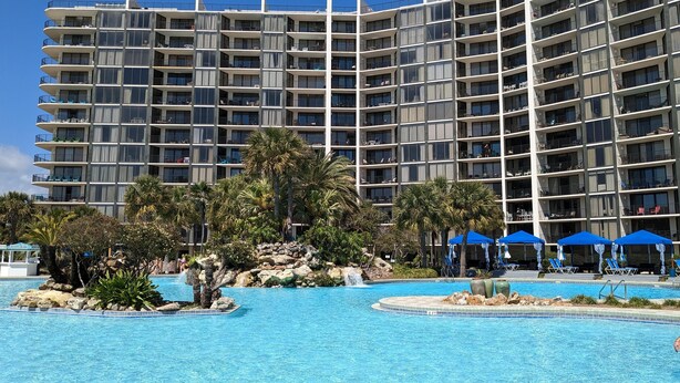 A multi-story hotel with balconies, a swimming pool, and palm trees. - Tower III, 7th floor Beachfront Master (Panama City Beach)