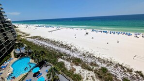 Um resort à beira-mar com piscina, guarda-sóis e vista desobstruída para o oceano.