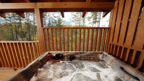 A hot tub with a wooden deck and a view of trees. - Walking Distance to Pool, Putt Putt, Fishing, Ping Pong & more! (Sevierville)