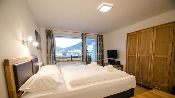 A hotel room with a large bed, a TV, and a wardrobe. - Deluxe Studio Kaprun TOP 23 (Kaprun)