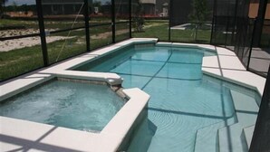 Ein Pool mit einem Whirlbereich, umgeben von einer Glaskonstruktion.