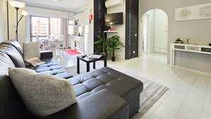 A modern living room with a grey sectional sofa, a small table, and a potted plant. - Gray Apartment Praia Rocha (Portimão)