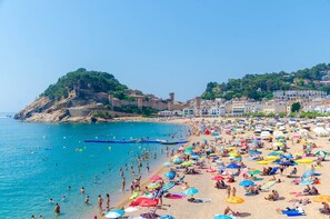 A crowded beach with numerous umbrellas and people enjoying the water.