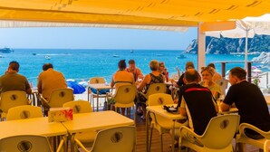 Un ristorante con tavoli e sedie gialle e una vista sul mare.