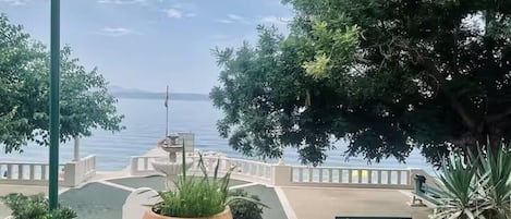 Une terrasse agrémentée de plantes en pot, d’un banc et offrant une vue sur une étendue d’eau.