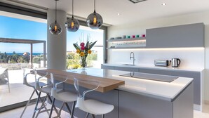 Een moderne keuken met een centraal eiland, barstoelen, hanglampen en uitzicht op de omgeving.