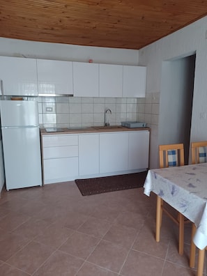 Eine Küche mit weißen Schränken, einem Edelstahlkühlschrank, einer Spüle und einem Esstisch mit Stühlen.