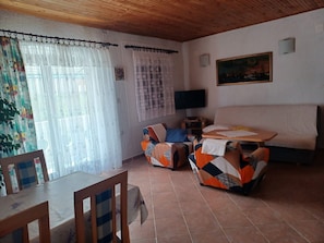 A room with a bed, a TV, a painting, and a dining area with chairs and a table. - Apartment in Murter with Terrace, Air condition, WIFI, Washing machine (125-1) (Murter)
