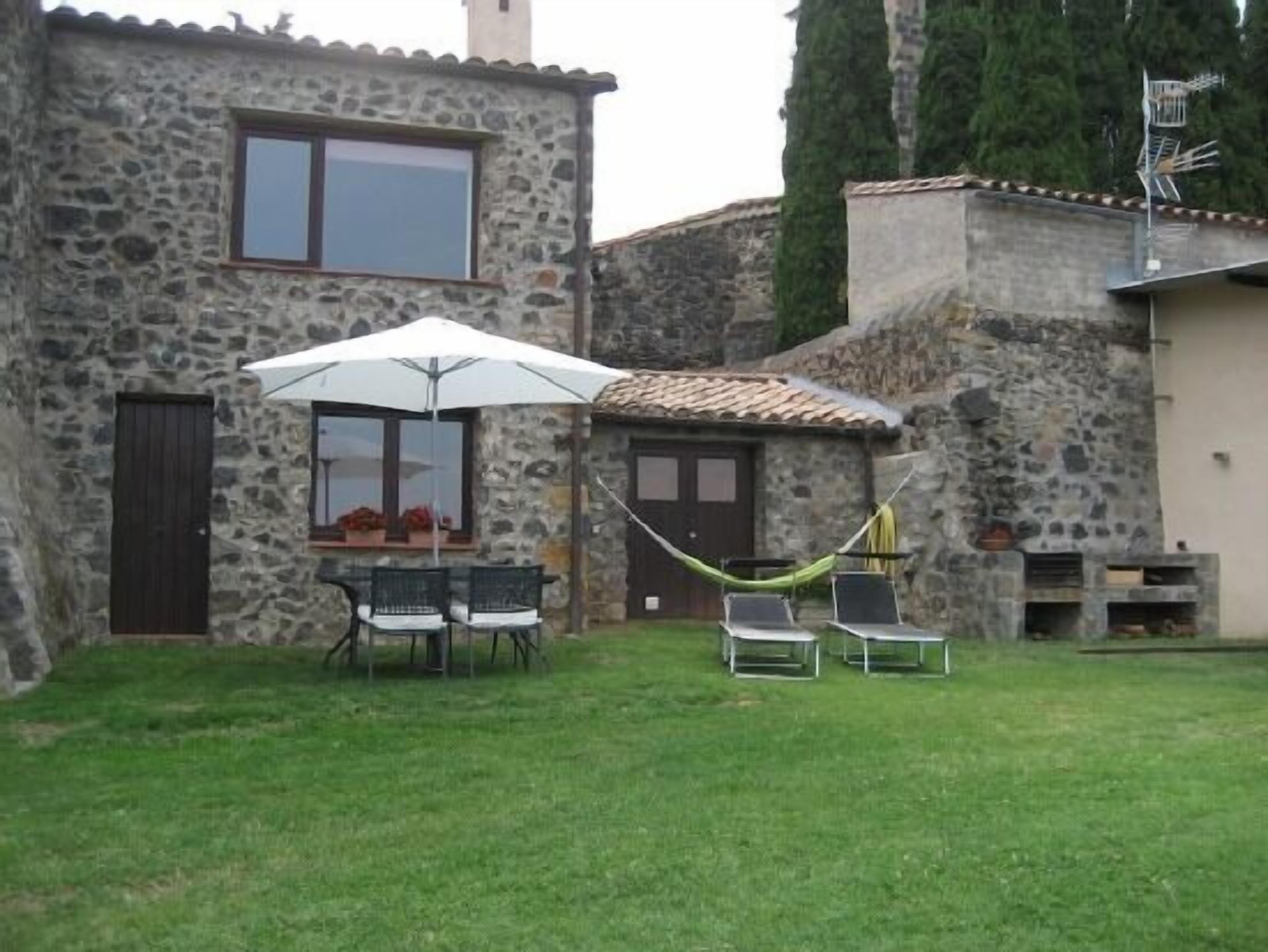 A stone house with a patio, a hammock, and outdoor seating.