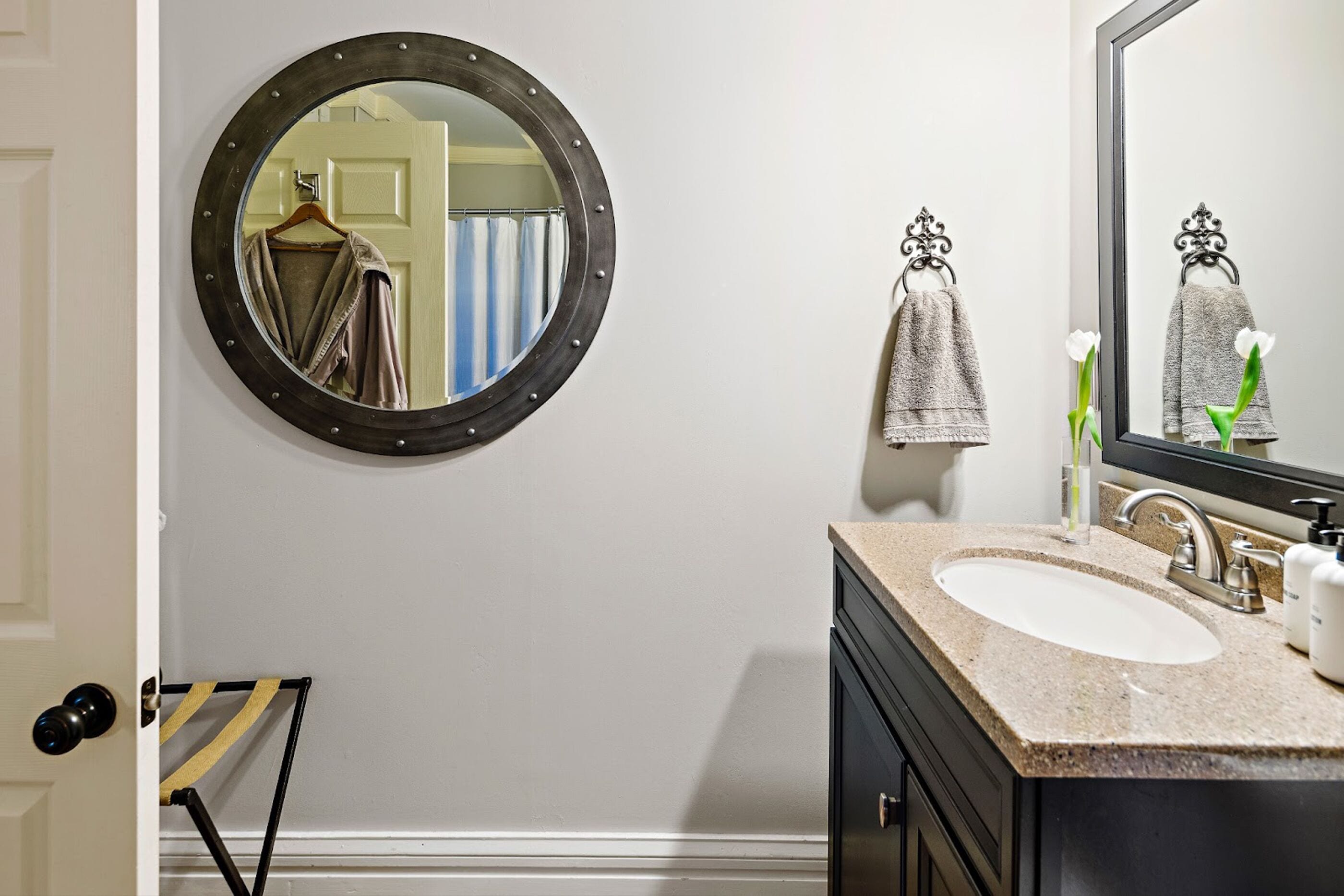 Une salle de bain avec un miroir rond, un lavabo et un porte-serviettes.