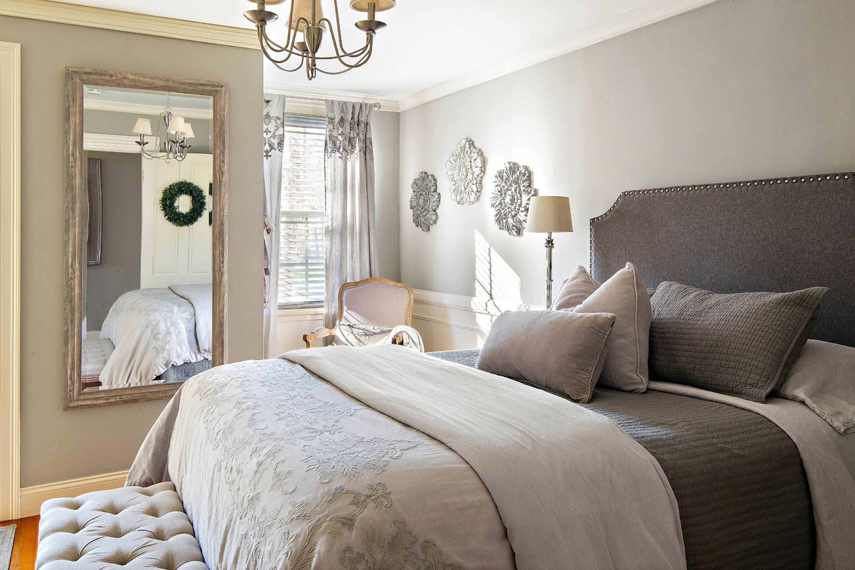 Una camera da letto con un letto grande, uno specchio, un lampadario e decorazioni a parete.