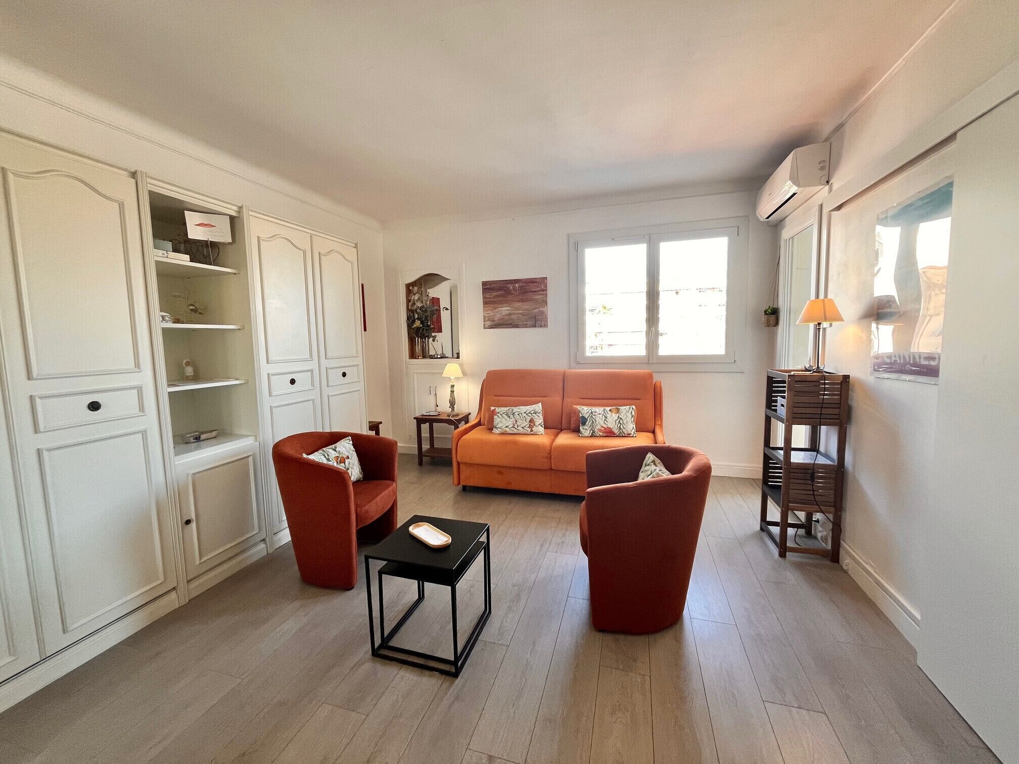 Ein Wohnzimmer mit einer Couch, zwei Sesseln, einem kleinen Tisch und einem Schrank.